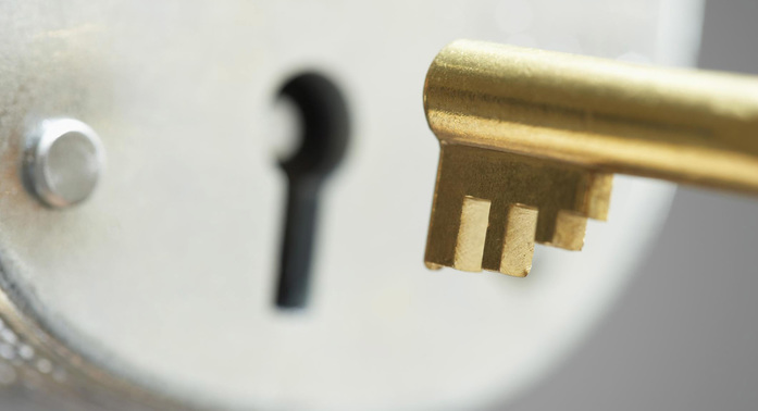 Guldnyckel som ska sättas in i rostfritt lås.